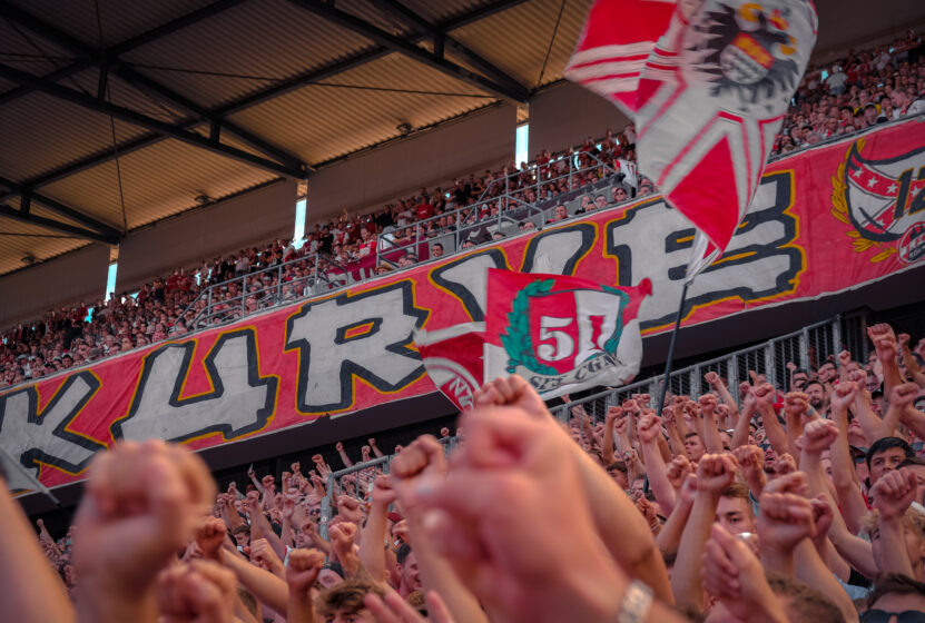 Fans beim Singen in der Südkurve. Im Hintergrund die Zaunfahne der Südkurve.